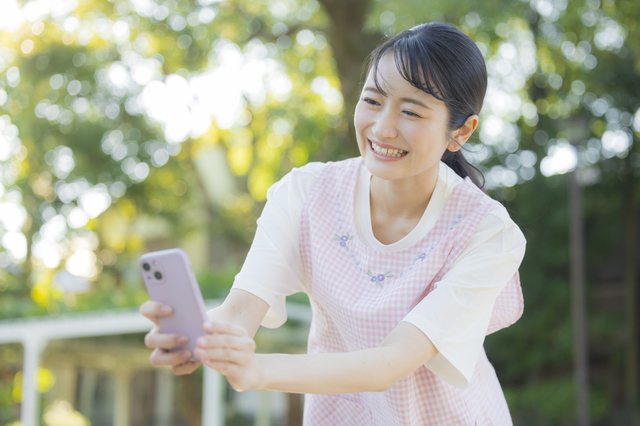 保育士がスマートフォンで園児の様子を撮影している様子